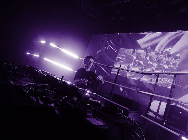 DJ aux platines Pioneer devant un écran de projection aux visuels abstraits